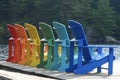 Row of multi coloured adirondack muskoka chairs on a dock Royalty Free Stock Photo
