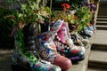 Row of multi-coloured leather painted boots with flowers growing in them Royalty Free Stock Photo