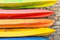 Row of multicolored kayaks against stonewall background Royalty Free Stock Photo