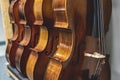 Row of multiple violins hanging on the wall, musician workshop