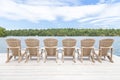 Row of Muskoka chairs on a dock looking onto the lake.