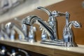 row of new chrome kitchen sink faucets displayed on shelf Royalty Free Stock Photo