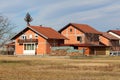 Row of newly built unfinished red brick family houses surrounded with dry grass and small wooden outdoor storage sheds Royalty Free Stock Photo