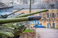 Row of numbers of military blow guns, cannons, howitzers against the backdrop of peaceful multi apartment houses. Guns painted by Royalty Free Stock Photo