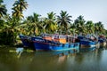 Row of ocean fishing boats from the front along the canal Kerala backwaters shore with palm trees between Alappuzha and Kollam,