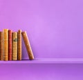 Row of old books on purple shelf. Square background Royalty Free Stock Photo