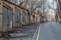 row of old brick garages with metal gates opening onto quiet empty city street running down