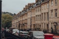Row of old stone terraced houses on a street in Bath, UK, cars parked in front