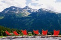 Row of orange lounge chairs facing breathtaking Austrian alpine panorama. Vorarlberg, Austria. Royalty Free Stock Photo