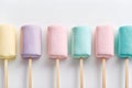 A row of pastel colored marshmallows, each in a different shade, offering a soft, sweet treat perfect for summer or food themes