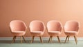 Row of peach colored armchairs on wooden floor near peach colored wall. Color of the year 2024