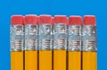 Row of pencil ends with erasers on blue background.