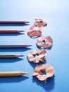 Row of pencils and sharpening shavings on blue background