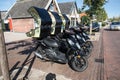 Row of pizza delivery motorbike scooters on pavement sidewalk of street waiting for use