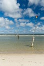 A row of poles marking the swimming area leading into the North Sea in Norderney with cloudy blue sky in the background