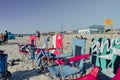 Row of portable beach chairs isolated on the beach with people having a rest under the clear sky