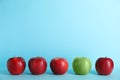 Row of red apples with green one on color background. Royalty Free Stock Photo