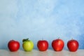 Row of red apples with green one on table. Royalty Free Stock Photo