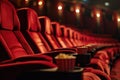 Row with red armchairs and popcorn cup holders in a cinema. Entertainment and movie watching concept