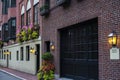 Row of red brick wall apartment buildings with flowers at window and lanterns. Garage below the apartment Royalty Free Stock Photo