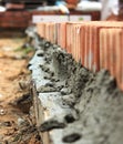 Row of Red Bricks on a Wall. Selective focus. Red bricks on top of a wall, spatula, red brick masonry, construction concept. Royalty Free Stock Photo