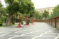 Row of red lampposts on a public park near green trees and a residential building