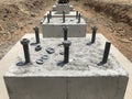 Row of reinforced concrete foundations with metal anchor bolts designed for the installation of metal columns Royalty Free Stock Photo