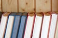 Row of retro books in hard color covers standing on bookshelf against wooden wall Royalty Free Stock Photo