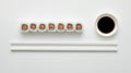 A row of salmon maki rolls with soy sauce and chopsticks on a white background surface Royalty Free Stock Photo