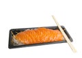 A row of Salmon Sashimi on vegetable slice in small black tray, a bamboo chopsticks on top, isolated and dicut on white background Royalty Free Stock Photo