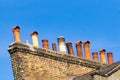 Row of several different style chimneys above roof tops
