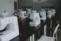 White sewing machines on the table. A row of sewing machines, a workshop for tailors