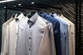 a row of shirts hanging on a rack in a room with a black and white wall behind them and a black and white wall behind them