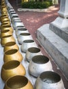 Row of silvery and golden alms bowls in buddhist temple