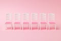 A row of six chairs on a pink background