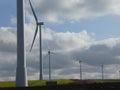 Row of six wind turbines surrounded by cottony clouds