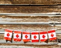 A row of small Canadian flags hanging on a rustic wooden wall
