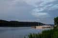 A row of small sailing boats lay moored, side by side, in a tranquil bay of lake Malaren, a summer morning in Sweden