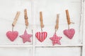 Row of small star and heart-shaped plush toys hanging from a string with clothespins on a white wall