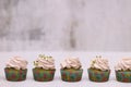 A row of spinach-mint cupcakes with fruit jam and berry cream on top