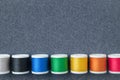 Row of spools of multicolored threads on sewing cloth. View from above. Copy space for text Royalty Free Stock Photo
