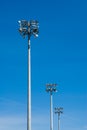 Row of stadium flood light towers on blue sky.