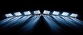 A row of stadium lights on a black background, casting beams of light downwards Royalty Free Stock Photo
