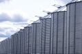 Row of stainless steel grain bins and cloudy sky Royalty Free Stock Photo