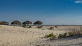 A row of straw sun umbrellas and deck chairs on the beach. Royalty Free Stock Photo