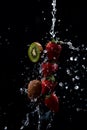 A Row of strawberries and kiwi being doused with plenty of water against a black background Royalty Free Stock Photo