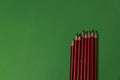 Row of striped pencils of different sharpness on the green background