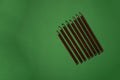 Row of striped pencils of different sharpness stacked diagonally on the green background
