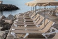 Row of sunbeds and parasols at the breakwater by the beach Playa de Puerto Rico on the Canary Island