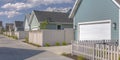 Row of sunlit houses with garages and white fences